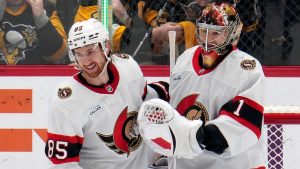 Ottawa Senators goaltender Leevi Merilainen (1) celebrates with Jake Sanderson (85) after time ran out in a shutout of the Pittsburgh Penguins in an NHL hockey game in Pittsburgh, Saturday, Jan. 11, 2025. (Gene J. Puskar/AP)