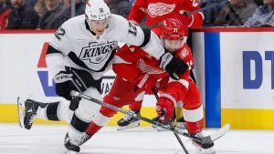 Los Angeles Kings left wing Trevor Moore (12) and Detroit Red Wings centre Dylan Larkin (71) chase a loose puck during the second period of an NHL hockey game Tuesday, Jan. 27, 2026, in Detroit. (Duane Burleson/AP)