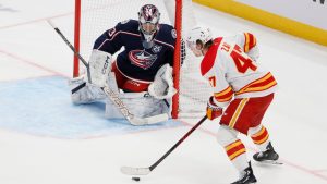 Columbus Blue Jackets' Jet Greaves, left, protects the net against Calgary Flames' Connor Zary during the second period of an NHL game, Tuesday, Jan. 13, 2026, in Columbus, Ohio. (AP/Jay LaPrete)