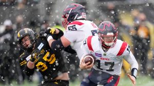 Montreal Alouettes quarterback Trevor Harris (17) scrambles as offensive lineman Landon Rice (55) blocks Hamilton Tiger-Cats defensive end Julian Howsare (95) during first half CFL division semi-final football action in Hamilton, Ont., on Sunday, November 28, 2021. (Nathan Denette/CP)