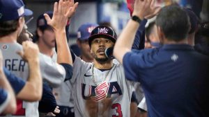 United States' Mookie Betts (3) is congratulated by teammates after he scored on a throwing error by Venezuela center fielder Ronald Acuna Jr., during the first inning of a World Baseball Classic game, Saturday, March 18, 2023, in Miami. (Wilfredo Lee/AP)