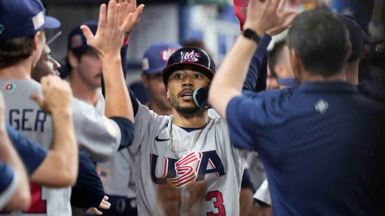 United States' Mookie Betts (3) is congratulated by teammates after he scored on a throwing error by Venezuela center fielder Ronald Acuna Jr., during the first inning of a World Baseball Classic game, Saturday, March 18, 2023, in Miami. (Wilfredo Lee/AP)