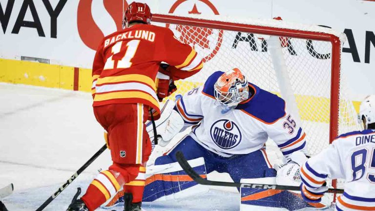 Edmonton Oilers' goalie Olivier Rodrigue (35) kicks the puck away from Calgary Flames' Mikael Backlund (11) during second period NHL preseason hockey action in Calgary, Monday, Sept. 23, 2024. (Jeff McIntosh/CP)
