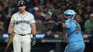 Seattle Mariners' Cal Raleigh, left, strikes out looking during the third inning in Game 4 of baseball's American League Championship Series as Toronto Blue Jays' Alejandro Kirk looks towards third base, Thursday, Oct. 16, 2025, in Seattle. (Abbie Parr/CP)