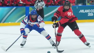 Kendall Coyne (26) of Team United States and Daryl Watts (95) of Team Canada battle for the puck during first period Olympic hockey action at the 2026 Milan Cortina Winter Olympics in Milan, Italy on Tuesday, Feb. 10, 2026. THE CANADIAN PRESS/Nathan Denette