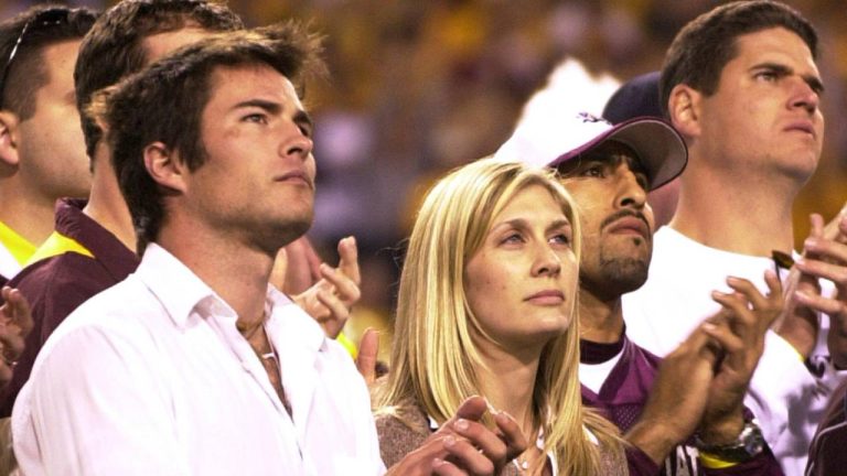 Former Arizona State player Pat Tillman's wife Marie Tillman, centre, and his brother Richard Tillman, left, applaud as they watch Pat's name and jersey number enshrined in the university's ring of honour. (AP Photo/Paul Connors)