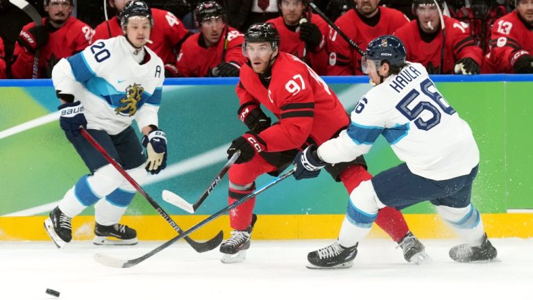 Canada forward Connor McDavid (97) moves the puck between Finland forward Sebastian Aho (20) and teammate Erik Haula (56) during second period Men's Olympic semifinal ice hockey action at the 2026 Milan Cortina Winter Olympics in Milan, Friday, Feb. 20, 2026. (Nathan Denette/CP)