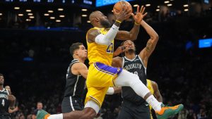 Los Angeles Lakers' LeBron James, center, drives past Brooklyn Nets' Nic Claxton, right, and Michael Porter Jr. during the first half of an NBA basketball game Tuesday, Feb. 3, 2026, in New York. (AP Photo/Frank Franklin II)