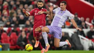 Liverpool's Mohamed Salah, left, challenges for the ball with Brighton's Lewis Dunk during the English Premier League soccer match between Liverpool and Brighton and Hove Albion in Liverpool, England, Saturday, Dec. 13, 2025. (AP Photo/Jon Super)