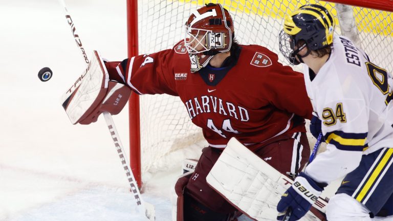 Former Harvard goalkeeper Mitchell Gibson, left, deflects the puck against Michigan's Mark Estapa during an NCAA hockey game on Friday, Nov. 25, 2022, in Ann Arbor, Mich. (Al Goldis/AP)