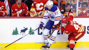 Edmonton Oilers' Connor McDavid, left, battles for the puck against Calgary Flames' Connor Zary during second period NHL hockey action in Calgary, Wednesday, Feb. 4, 2026. (Larry MacDougal/CP)