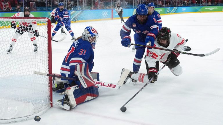 United States goalie Aerin Frankel (31) makes the save as teammate Caroline Harvey (4) checks Canada's Laura Stacey (7) during the first period of the women's gold medal hockey game at the 2026 Winter Olympics, in Milan, Thursday, Feb. 19, 2026. (Darryl Dyck/CP)