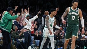 Fans, left, react after Boston Celtics guard Anfernee Simons (4) hit a 3-point basket as the buzzer sounded for the end of the first quarter of an NBA game against the Milwaukee Bucks, Sunday, Feb 1, 2026, in Boston. (AP Photo/Jim Davis)