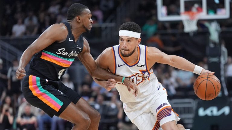 Phoenix Suns guard Devin Booker (1) drives against San Antonio Spurs guard De'aaron Fox (4) during the first half of an NBA basketball game in Austin, Texas, Thursday, Feb. 19, 2026. (AP Photo/Eric Gay)
