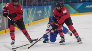 United States' Britta Curl is challenged by Canada's Emily Clark during a preliminary round match of women's ice hockey between USA and Canada at the 2026 Winter Olympics, in Milan, Italy, Tuesday, Feb. 10, 2026. (AP Photo/Petr David Josek)