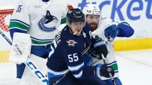 Vancouver Canucks' Filip Hronek (17) defends against Winnipeg Jets' Mark Scheifele (55) during third period NHL action in Winnipeg on Sunday, March 30, 2025. (John Woods/CP)