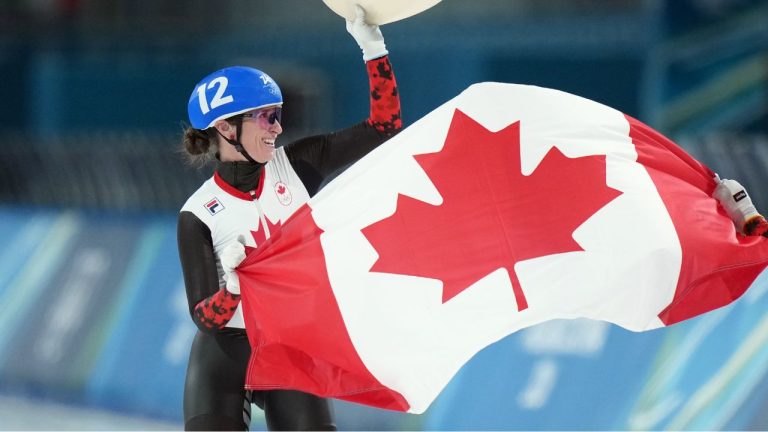 Canada's Ivanie Blondin (12) waves the maple leaf flag with teammate Valerie Maltais (7) after running the women's mass start speedskating finals at the 2026 Winter Olympics, in Milan, Saturday, Feb. 21, 2026. Blondin finished second for the silver medal, while Maltais recovered from a fall early in the race to finish fifth. (Darryl Dyck/THE CANADIAN PRESS)
