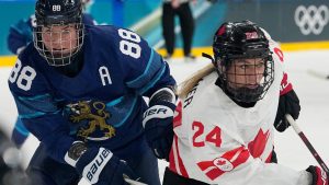Finland's Ronja Savolainen, left, challenges Canada's Natalie Spooner during a preliminary round match of women's ice hockey between Finland and Canada at the 2026 Winter Olympics, in Milan, Italy, Thursday, Feb. 12, 2026. (Hassan Ammar/AP)