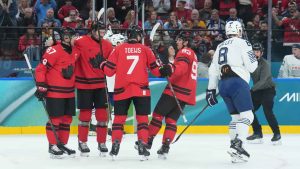 Devon Toews (7) of Team Canada celebrates his goal with teammates as Hugo Gallet (8) of Team France skates by during first period Olympic hockey action at the 2026 Milan Cortina Winter Olympics in Milan, Italy. (Nathan Denette/THE CANADIAN PRESS)