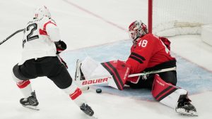 Canada's goalkeeper Logan Thompson, right, makes a save against Switzerland's Nino Niederreiter during a preliminary round match of men's ice hockey between Canada and Switzerland at the 2026 Winter Olympics, in Milan, Italy, Friday, Feb. 13, 2026. (Hassan Ammar/AP)