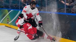 Canada's Natalie Spooner, top, fights for the puck with Switzerland's Annic Buchi during a preliminary round match of women's ice hockey between the Switzerland and Canada at the 2026 Winter Olympics. (Petr David Josek/AP)
