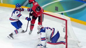 Canada's Connor McDavid (97) is stoped by United States goalie Connor Hellebuyck (37) as United States' Brock Faber (14) defends during the second period of the men's gold medal hockey game at the 2026 Winter Olympics. (Darryl Dyck/THE CANADIAN PRESS)