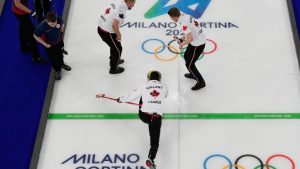 Canada's Brett Gallant delivers the stone as Ben Hebert and Marc Kennedy prepare to sweep during a men's curling round robin match against Czechia at the 2026 Winter Olympics, in Cortina d'Ampezzo, Italy, Monday, Feb. 16, 2026. (David J. Phillip/AP Photo)