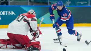 United States' Jack Hughes, right, shoots against Denmark's goalkeeper Mads Sogaard during a preliminary round match of men's ice hockey between United States and Denmark at the 2026 Winter Olympics, in Milan, Italy, Saturday, Feb. 14, 2026. (Petr David Josek/AP)