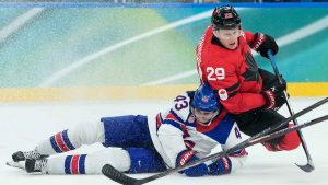 Canada's Nathan MacKinnon (29) falls on United States' Quinn Hughes (43) during a men's ice hockey gold medal game between Canada and the United States at the 2026 Winter Olympics, in Milan. (Petr David Josek/AP)