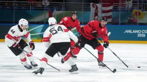 Canada's Connor McDavid (97) tries to get around Switzerland's Christian Marti (54) and Pius Suter (44) during the first period of a preliminary round men's hockey game at the 2026 Winter Olympics, in Milan, on Friday, Feb. 13, 2026. (Darryl Dyck/CP)