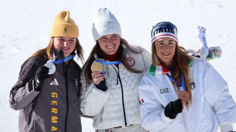 United States' Breezy Johnson, centre, winner of the gold medal in the alpine ski women's downhill race, poses with silver medallist Germany's Emma Aicher, left, and bronze medallist Italy's Sofia Goggia, at the 2026 Winter Olympics, in Cortina d'Ampezzo, Italy, Sunday, Feb. 8, 2026. (Marco Trovati/AP Photo)