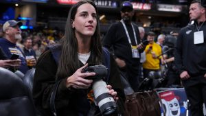 Indiana Fever guard Caitlin Clark takes photos during pregame before an NBA basketball game between the Indiana Pacers and the Los Angeles Lakers in Indianapolis, Wednesday, March 25, 2026. (Michael Conroy/AP)