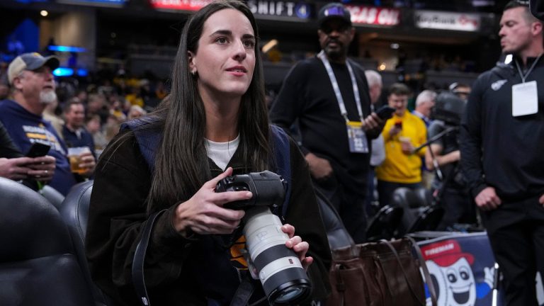 Indiana Fever guard Caitlin Clark takes photos during pregame before an NBA basketball game between the Indiana Pacers and the Los Angeles Lakers in Indianapolis, Wednesday, March 25, 2026. (Michael Conroy/AP)