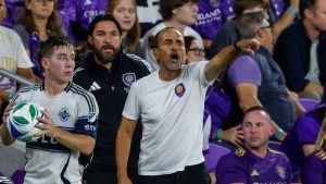 Orlando City manager Óscar Pareja communicates to his team as Vancouver Whitecaps defender Tate Johnson, left, goes to in the ball during the second half of an MLS soccer match, Saturday, Oct. 11, 2025, in Orlando, Fla. (AP Photo/Kevin Kolczynski)