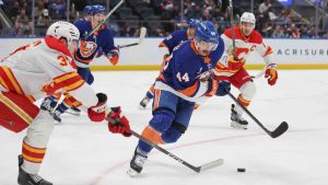 New York Islanders center Jean-Gabriel Pageau (44) takes the puck from Calgary Flames defenseman Yan Kuznetsov, left, during the first period of an NHL hockey game, Saturday, March 14, 2026, in Elmont, N.Y. (Heather Khalifa/AP)