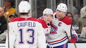 Montreal Canadiens centre Nick Suzuki, right, celebrates his goal with right wing Cole Caufield, left, and defenceman Lane Hutson during the third period of an NHL hockey game against the Los Angeles Kings, Saturday, March 7, 2026, in Los Angeles. (Mark J. Terrill/AP)