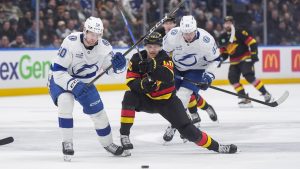 Tampa Bay Lightning's J.J. Moser, left, lifts Vancouver Canucks' Elias Pettersson's stick as they vie for the puck during the third period of an NHL hockey game, in Vancouver, on Thursday, March 19, 2026. (Darryl Dyck/CP)