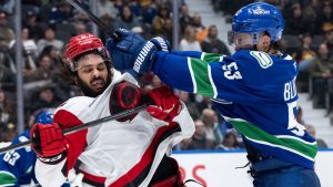 Vancouver Canucks' Teddy Blueger (53) hits Carolina Hurricanes' Jalen Chatfield (5) during the third period of an NHL hockey game in Vancouver, on Wednesday, March 4, 2026. (Ethan Cairns/CP)