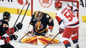 Carolina Hurricanes' Eric Robinson, right, has his shot stopped by Calgary Flames goalie Dustin Wolf during first period NHL hockey action in Calgary on Saturday, March 7, 2026. (Jeff McIntosh/CP)