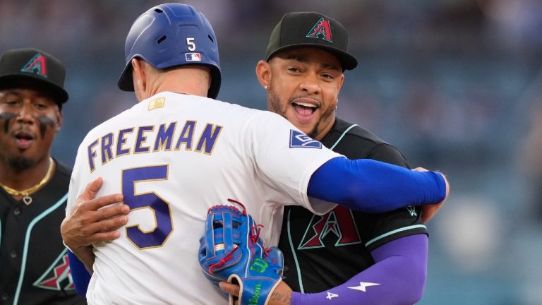 Arizona Diamondbacks second baseman Ketel Marte, right, hugs Los Angeles Dodgers' Freddie Freeman, left, after tagging him out on a fielder's choice by Santiago Espinal as shortstop Geraldo Perdomo runs behind during the second inning of a baseball game Saturday, March 28, 2026, in Los Angeles. (Mark J. Terrill/AP)