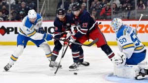 Winnipeg Jets' Adam Lowry (17) and Gabriel Vilardi (13) try to control the puck in front of St. Louis Blues' goaltender Jordan Binnington (50) as Justin Holl (4) defends during second period NHL hockey in Winnipeg, Sunday March 15, 2026. (Fred Greenslade/CP)