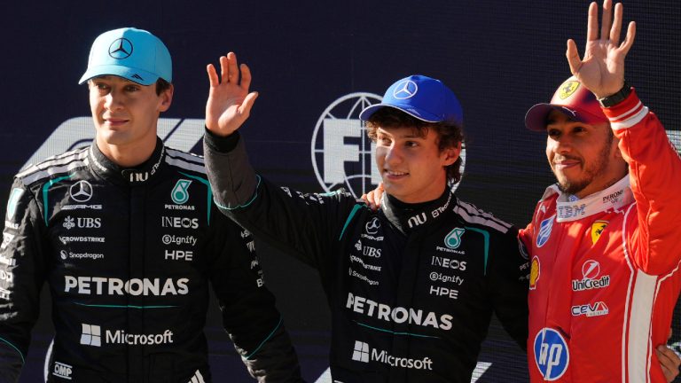 Mercedes driver Andrea Kimi Antonelli of Italy, center, waves after getting the pole position beside Mercedes driver George Russell, left, of Britain and Ferrari driver Lewis Hamilton of Britain during the qualifying session of the Chinese Formula One Grand Prix at the Shanghai International Circuit, in Shanghai, China, Saturday, March 14, 2026. (Vincent Thian/AP)