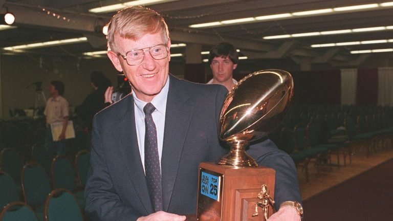 FILE - Notre Dame head coach Lou Holtz carries away the National College Champion Trophy following a news conference in Tempe, Ariz. in this Jan. 3, 1989 photo. (Rob Schmacher/AP)