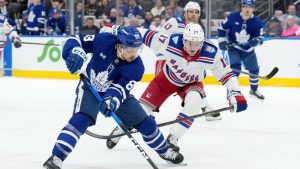 Toronto Maple Leafs forward Nicholas Robertson (89) drives the puck past New York Rangers defenceman Will Borgen (17) during second period NHL hockey action in Toronto, Wednesday, March 25, 2026. (Nathan Denette/CP)