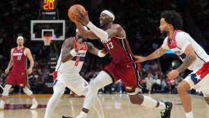 Miami Heat center Bam Adebayo (13) drives past Washington Wizards guard Jaden Hardy (8) and forward Justin Champagnie (9) during the second half of an NBA basketball game, Tuesday, March 10, 2026, in Miami. (Rebecca Blackwell/AP)