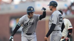 New York Yankees' Cody Bellinger, left, gestures toward teammates next to first base coach Dan Fiorito after hitting a single against the San Francisco Giants during the fifth inning of a baseball game in San Francisco, Wednesday, March 25, 2026. (Jeff Chiu/AP)