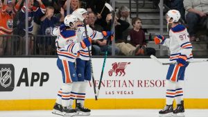 Edmonton Oilers defenseman Evan Bouchard , center, celebrates after scoring against the Vegas Golden Knights during overtime of an NHL hockey game Thursday, March 26, 2026, in Las Vegas. (AP Photo/John Locher)