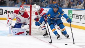 St. Louis Blues' Robert Thomas, right, reaches for a loose puck as Montreal Canadiens goaltender Jacob Fowler (32) and Nick Suzuki (14) defend during the second period of an NHL hockey game Saturday, Jan. 3, 2026, in St. Louis. (AP Photo/Jeff Roberson)