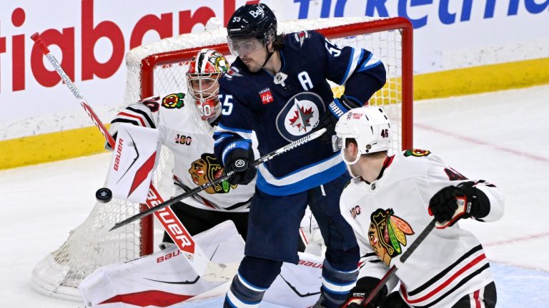 Winnipeg Jets' Mark Scheifele (55) looks to tip a shot in front of Chicago Blackhawks goaltender Spencer Knight (30) during the first period of their NHL hockey game in Winnipeg, Tuesday March 3, 2026. (Fred Greenslade/CP)