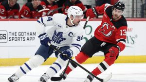 Toronto Maple Leafs center Auston Matthews (34) controls the puck past New Jersey Devils center Nico Hischier (13) during the second period of an NHL hockey game Wednesday, March 4, 2026, in Newark, N.J. (AP Photo/Adam Hunger)